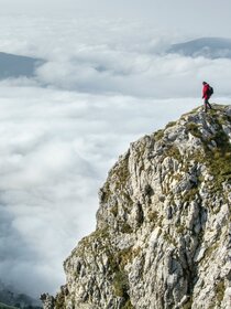 Man standing on edge of cliff with clouds