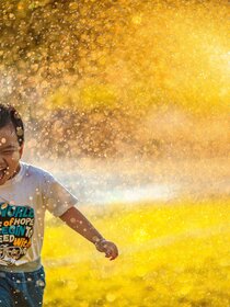Image of smiling kid running through sprinkler