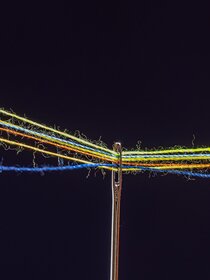 different colored threads through the eye of a needle on a black background
