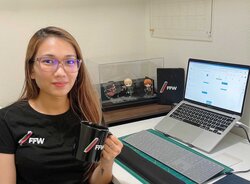 Woman with FFW shirt and mug working on laptop