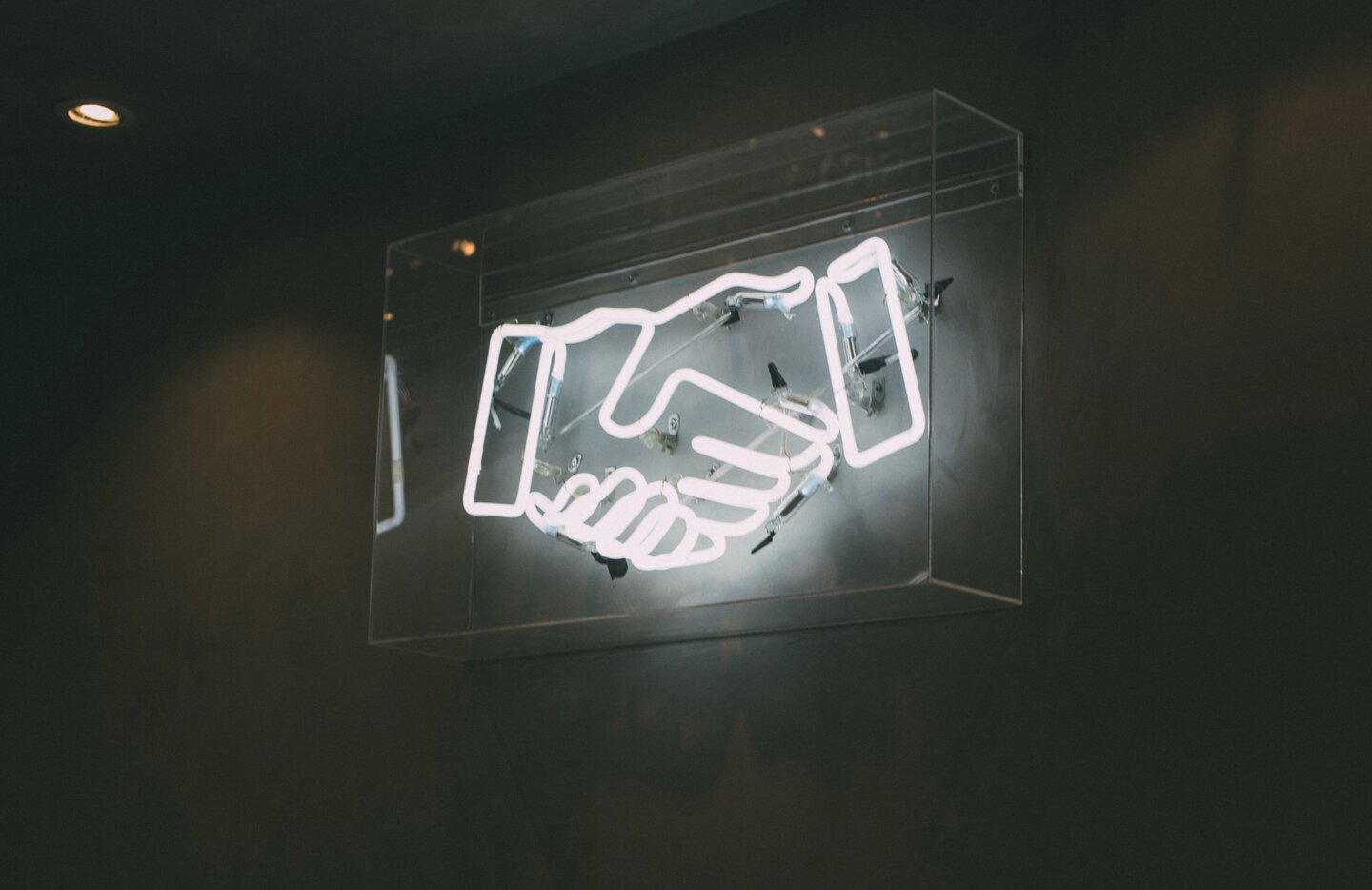 Image of neon sign of hands shaking