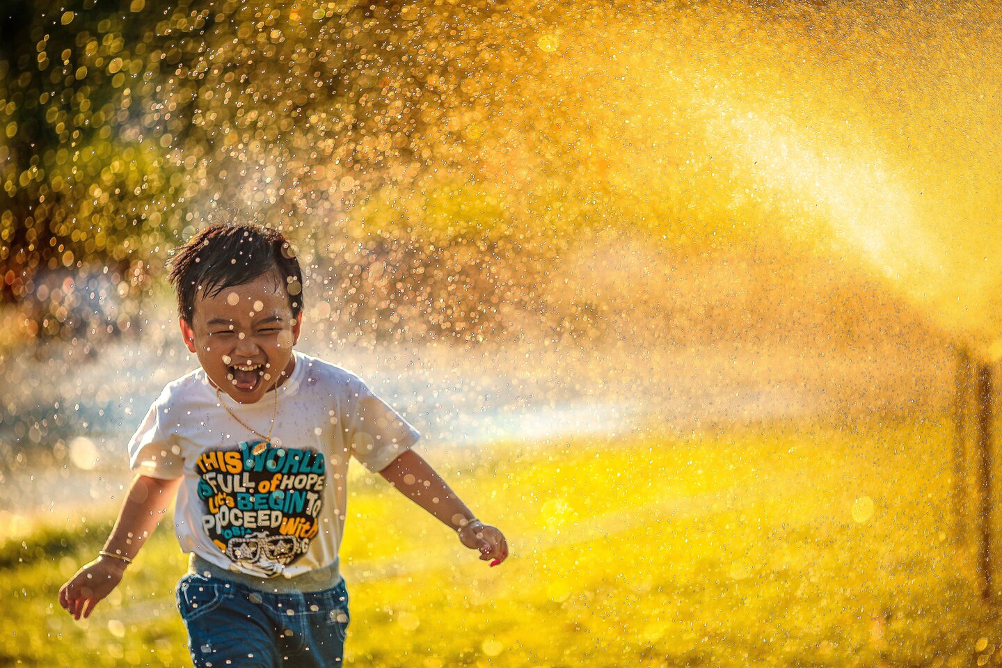 Image of smiling kid running through sprinkler